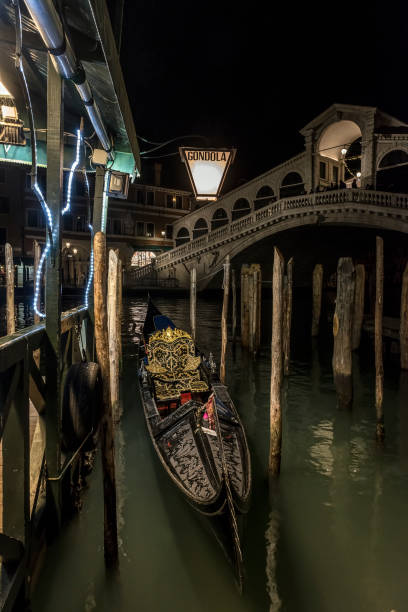 Rialto Bridge and illuminated gondola sign at night in Venice