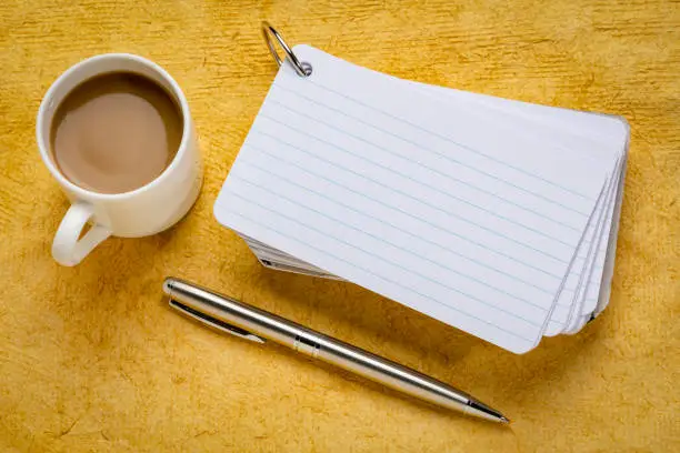 stack of blank index cards with a cup of coffee and  a pen against yellow textured paper