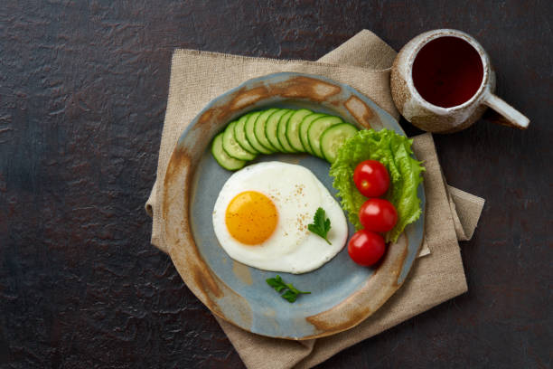istock Fried egg, vegetables. Paleo, keto, fodmap diet. Copy space, top view. Healthy diet concept, blue plate on dark concrete table 1131075622