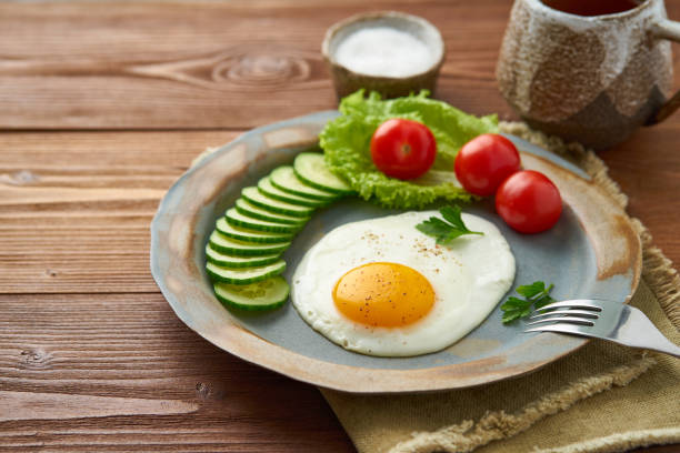 istock Fried egg, vegetables. Paleo, keto, fodmap diet. Side view. Healthy diet concept, blue plate on old rustic wooden table 1131075644