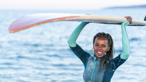 istock Female surfer holding surfboard and walking on beach 1131083150