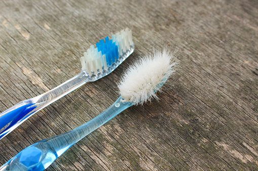 Old and new toothbrushes on old wooden background.