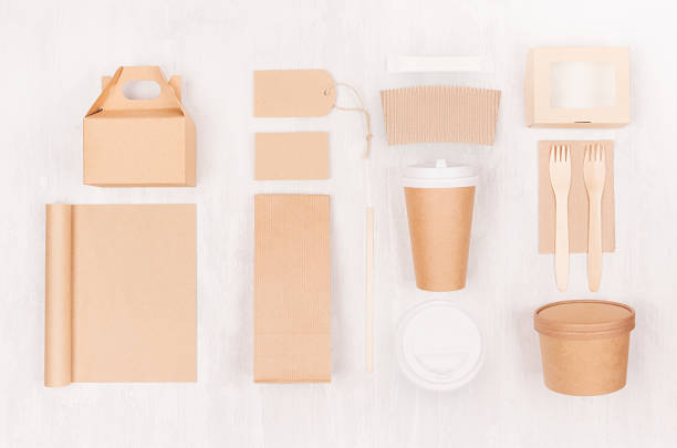 istock Blank different cardboard packaging for fast food - coffee cup, notebook, cutlery, sugar, spice, container and box for soup, sushi, burger on white wood board. 1131086360