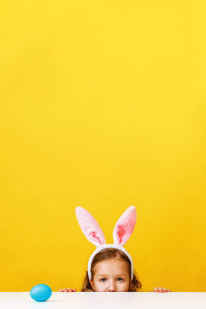 家でウサギの耳を持つかわいい子供の女の子は、イースターエッグを探しています。 - easter egg easter yellow paint ストックフォトと画像