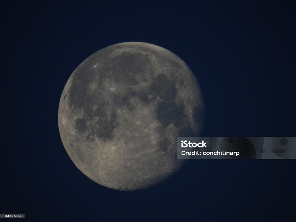 Full Moon on Blue sky Large full moon in detail with the geographical features, craters and edges visible. Above Stock Photo