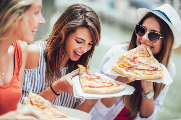 istock Three beautiful young women eating pizza after shopping, having fun together. 1131096276