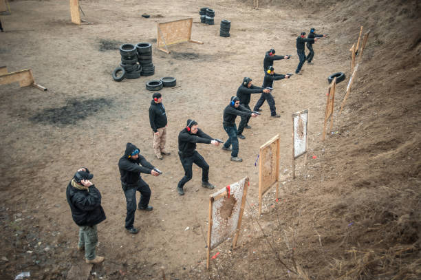 os estudantes agrupam com instrutores praticam o tiro da arma na escala de tiro - big time fotos - fotografias e filmes do acervo