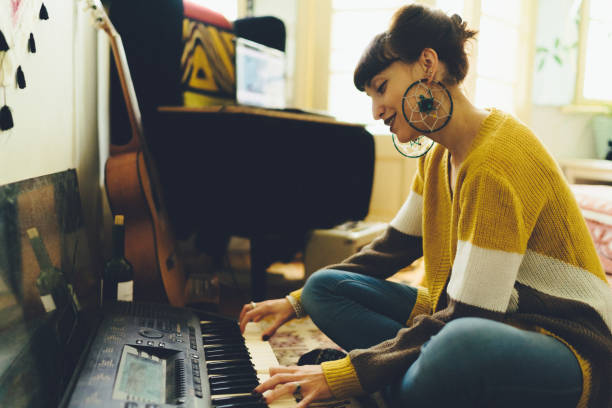 Woman composing music Hippie woman sitting on floor and playing on synthesizer offbeat stock pictures, royalty-free photos & images