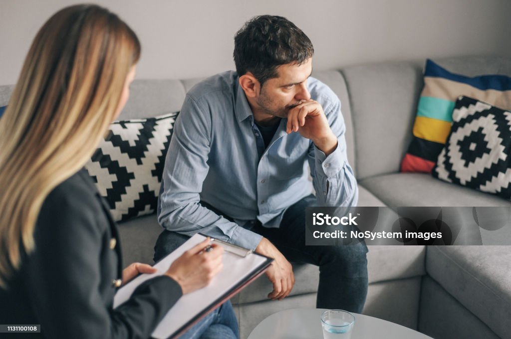 Young man, alcoholic, on  therapy session Young man, alcoholic, talking to female therapist about his problems, on  therapy session Psychotherapy Stock Photo