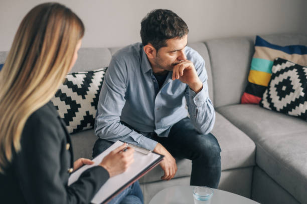 Young man, alcoholic, on  therapy session Young man, alcoholic, talking to female therapist about his problems, on  therapy session dependency photos stock pictures, royalty-free photos & images