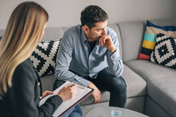 Young man, alcoholic, on therapy session Young man, alcoholic, talking to female therapist about his problems, on therapy session alternative therapy stock pictures, royalty-free photos & images