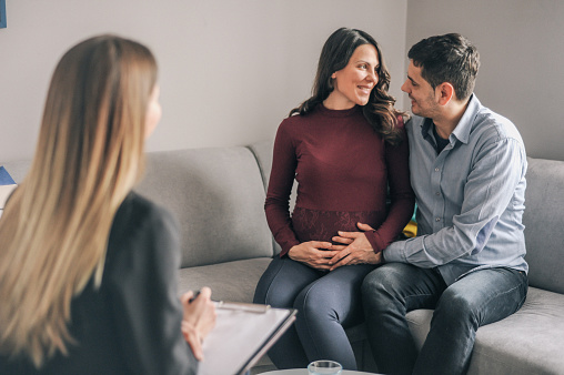 Young couple on counseling appointment, talking about pregnancy with therapist