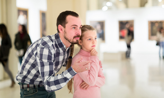 Male and small daughter looking  pictorial art in halls