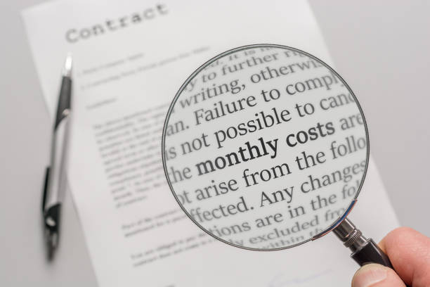 Contract is checked with a magnifying glass on the subject of monthly costs as a result of a contract Check the fine print carefully read the fine print stock pictures, royalty-free photos & images