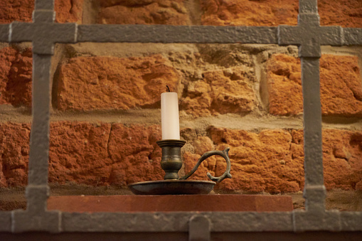 A candlestick behind a grid in front of a brick wall