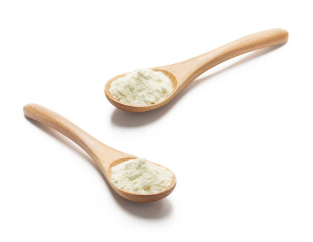 Wooden spoon filled with milk powder stock photo