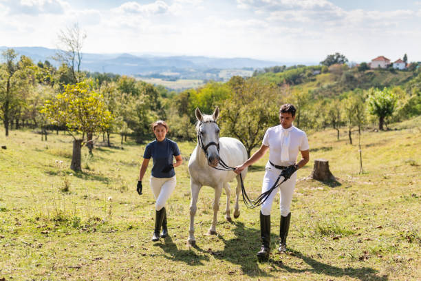 Horseback riders walking a white horse