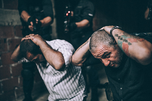 Group of man, special police forces in abandoned house, making an arrest on criminals.