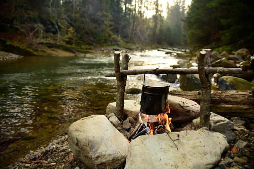 Cooking on bonfire. Campfire near mountain river. Camping fire on the river bank. Concept  travel, hiking and adventure