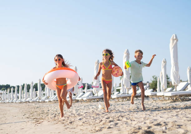 die kids laufen am strand. - swim ring stock-fotos und bilder