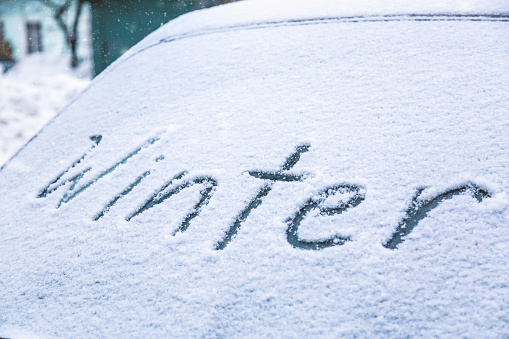 Word winter on the frozen glass of a car windshield. Car winter season concept