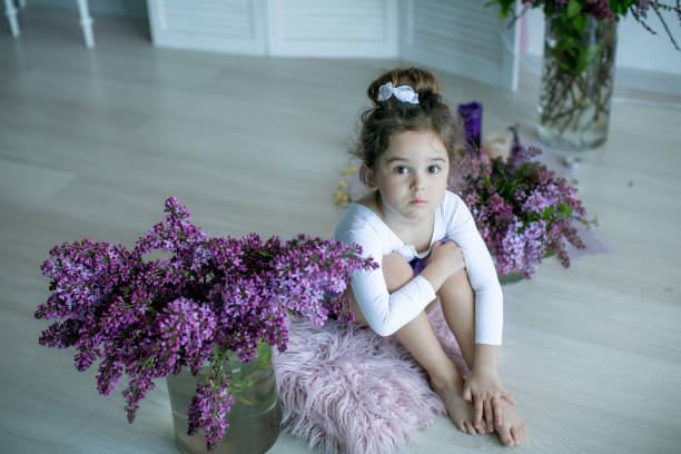 entzückendes kleines mädchen, das als ballerina in einem tutu gekleidet ist, ihre ballettschuhe einbindet. - ballet dress studio shot costume stock-fotos und bilder