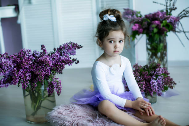 entzückendes kleines mädchen, das als ballerina in einem tutu gekleidet ist, ihre ballettschuhe einbindet. - ballet dress studio shot costume stock-fotos und bilder
