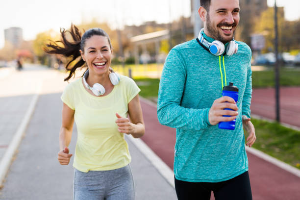 istock Young attractive couple running outside on sunny day 1131122944