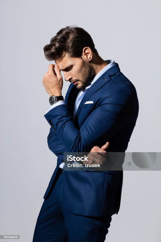 Thoughtful young businessman Portrait of young businessman thinking against gray background Men Stock Photo