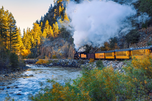 Historic steam engine train travels from Durango to Silverton through the San Juan Mountains along the Animas River in Colorado, USA.