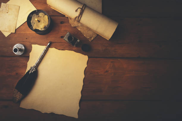 перо перо и старая пергаментная бумага на коричневом деревянном столе. вид сверху - ink well paper document quill pen стоковые фото и изображения