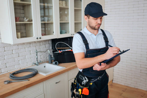 istock Busy young handyman stan in kitchen and white on plastic tablet. Toolbox and hose on desk. Daylight. Man in uniform. 1131133064