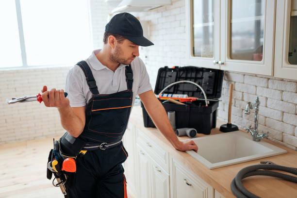 istock Serious busy young worker lean to sink in kitchen and look at it. He hold wrench. Toolbox and hose on desk. Daylight. 1131133076