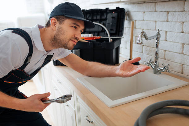 istock Young handyman check tap for leaking. He hold hand under it. Man stand in kitchen at sink. Toolbox and hose on desk. 1131133082
