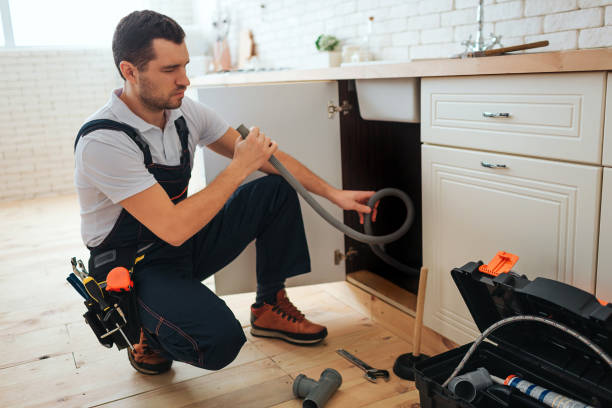 istock Concentrated young worker doing repairing in kitchen. He sit in squad pose and hold hose. Piece of pipe on floor. Opened toolbox. 1131133084