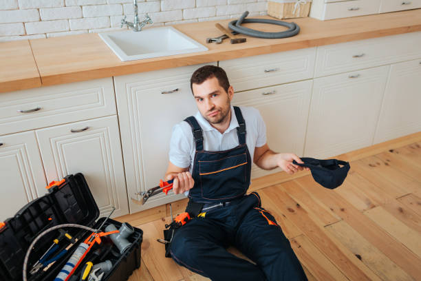 istock Handyman sit on floor in kitchen. He look on camera confusingly. Guy hold cap and wrench. Having rest. 1131133095