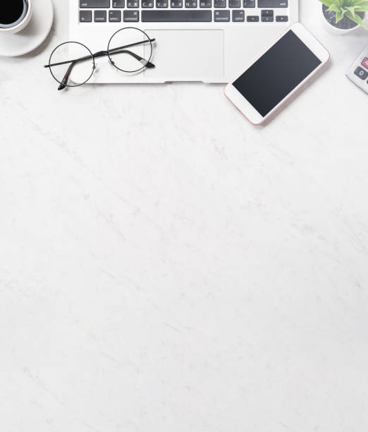 istock Stylized clean marble office working desk with smartphone, laptop, glasses and coffee cup, workspace design, mock up, top view, flat lay, copy space, close up 1131136562