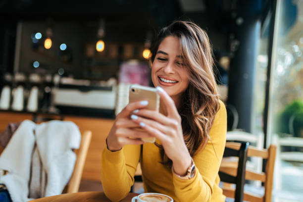 señora feliz usando el teléfono móvil en el café. - dispositivo de información móvil fotografías e imágenes de stock