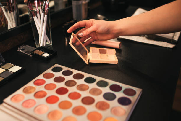 istock Hand hold mirror. Eyeshadows palette lying on black table. Brushes in glass. Cut view. Close up. 1131138783