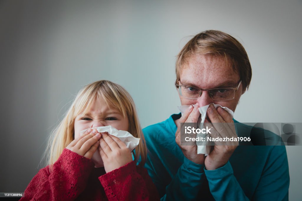 father and daughter wiping and blowing nose, infection or allergy father and daughter wiping and blowing nose, family infection or allergy Adult Stock Photo