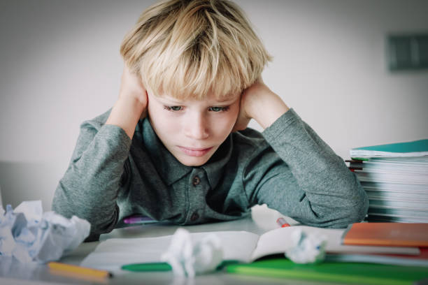 istock little boy tired stressed of reading, doing homework 1131140722