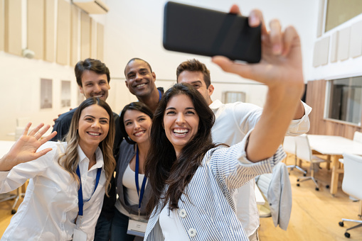 Portrait of a happy group of coworkers taking a selfie at a creative office using a cell phone - lifestyle concepts