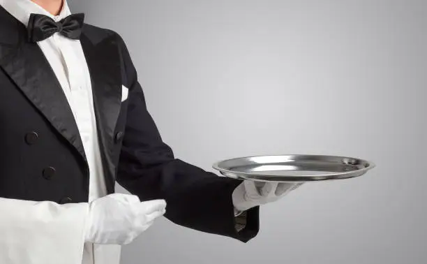 Waiter serving with white gloves and steel tray in an empty space