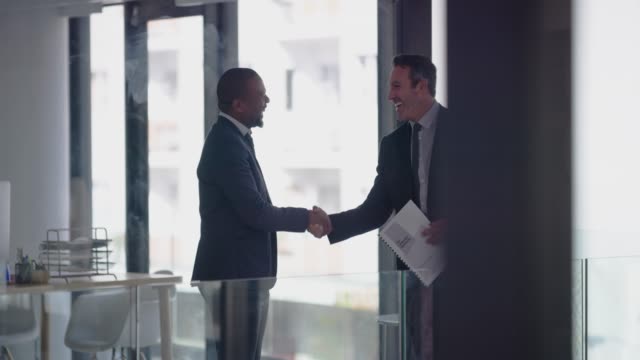 4k video footage of two businessmen shaking hands in a modern office