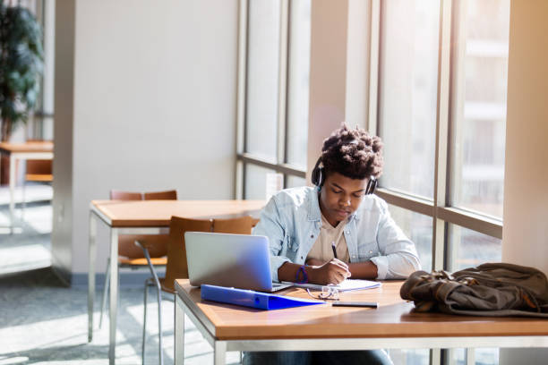 istock Teenage boy enjoys music while he studies at school 1131145985