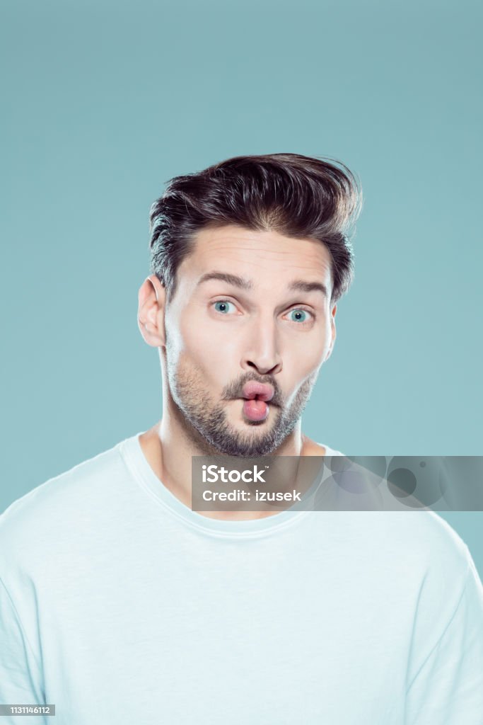 Young man with fish lips Close up portrait of young caucasian man with fish lips against gray background Men Stock Photo