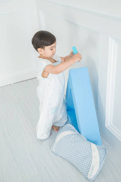 istock In the nursery's bedroom, next to a blue triangular cube, a cute little boy plays with pillows and blocks 1131147185