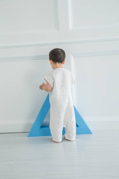 istock In the nursery's bedroom, there is a blue triangle cube, a small boy in a nightgown, running around happily 1131147687