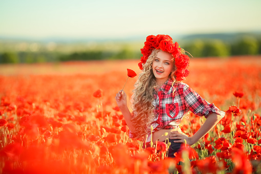 Portrait of a girl on the street with a wreath of poppy flowers on the head.