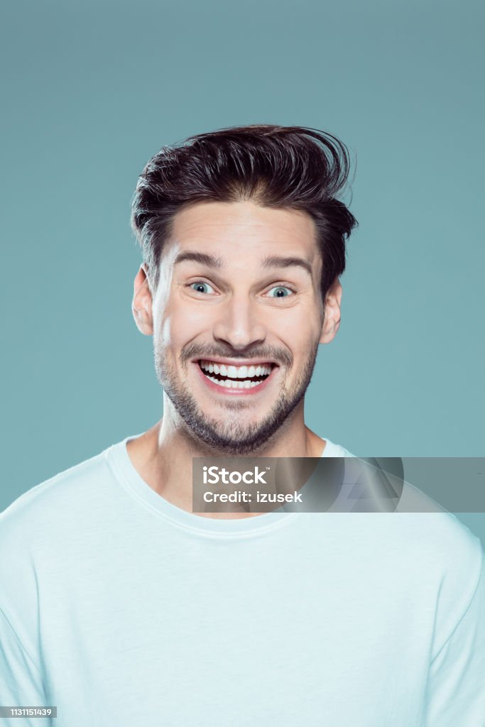 Young man with funny facial expression Close up portrait of young man with funny facial expression against gray background Close-up Stock Photo